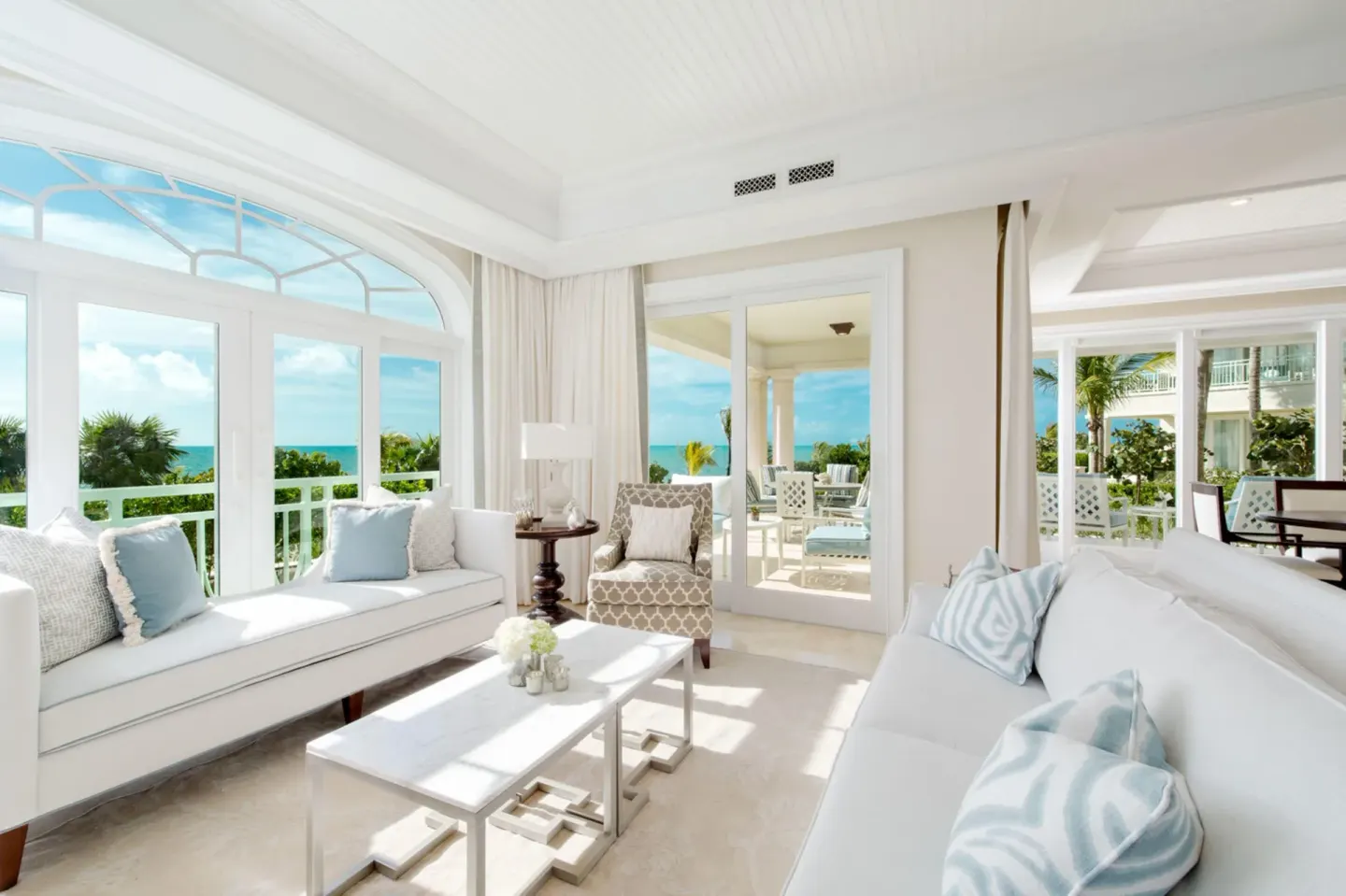Oceanfront living room with sofas, balcony doors, and sea view at The Shore Club Turks and Caicos.