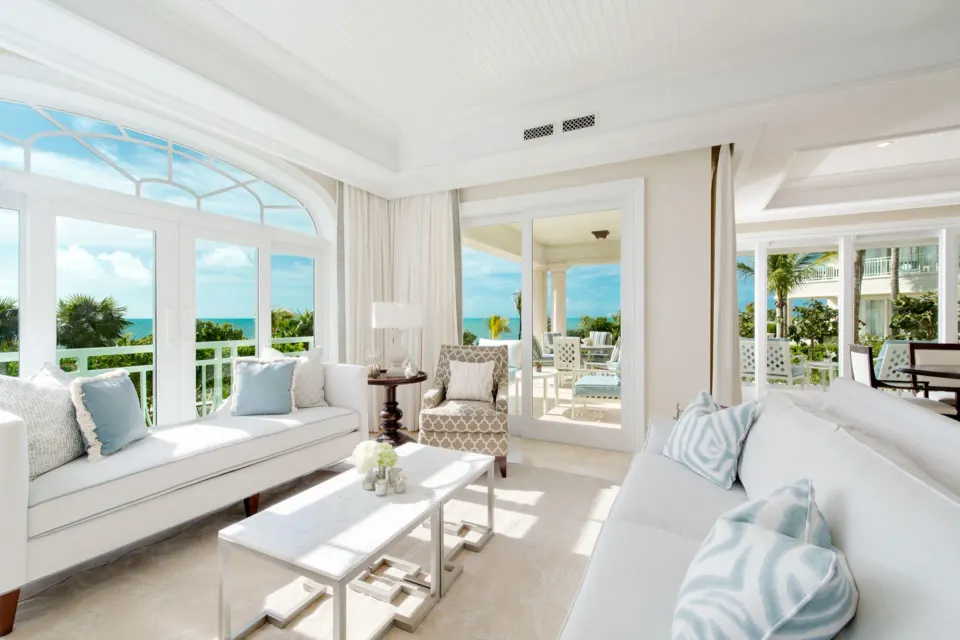 Oceanfront living room with sofas, balcony doors, and sea view at The Shore Club Turks and Caicos.