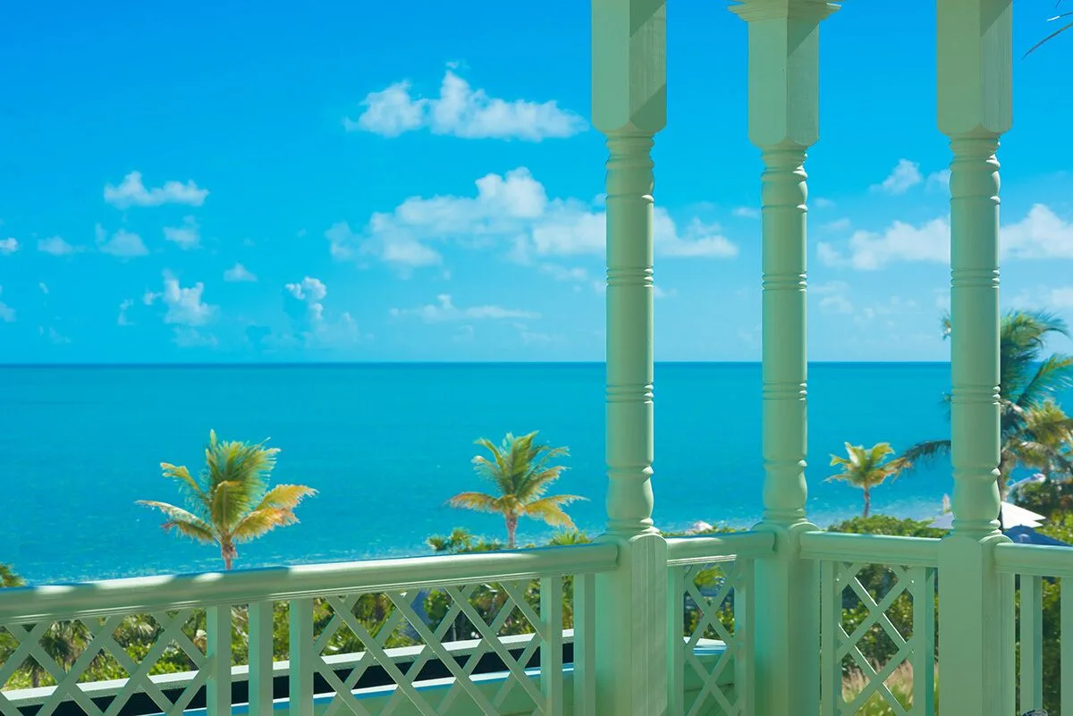 Balcony view from a Luxury Villa at The Shore Club Turks and Caicos with turquoise sea and palm trees.