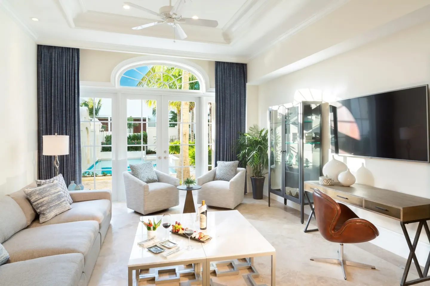 Luxury villa sitting room with sofa, TV, and pool-facing doors at The Shore Club Turks and Caicos.