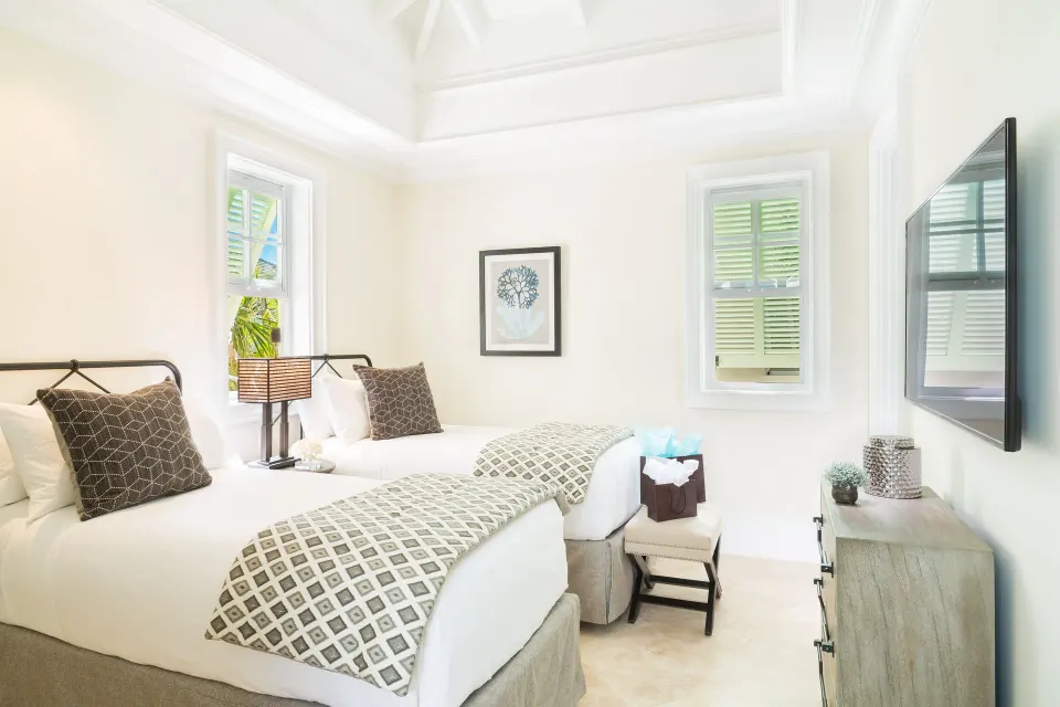 Twin bedroom in a Luxury Villa at The Shore Club Turks and Caicos with shuttered windows and wall TV.