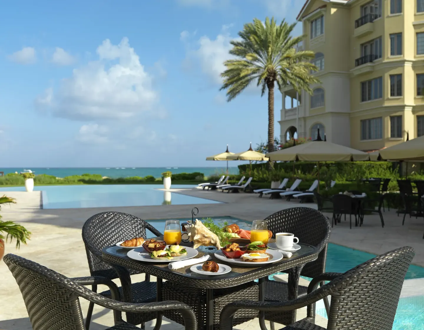 Poolside breakfast table with ocean backdrop at The Somerset on Grace Bay.