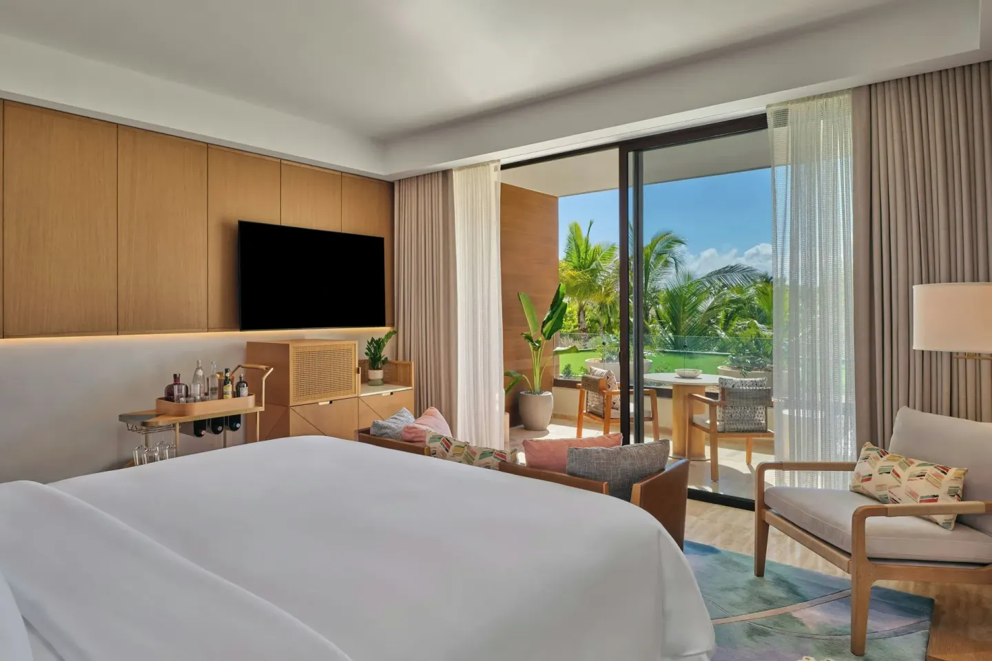 King bed, TV wall, minibar cart, and balcony in a Superior Room at The St Regis Cap Cana Resort.