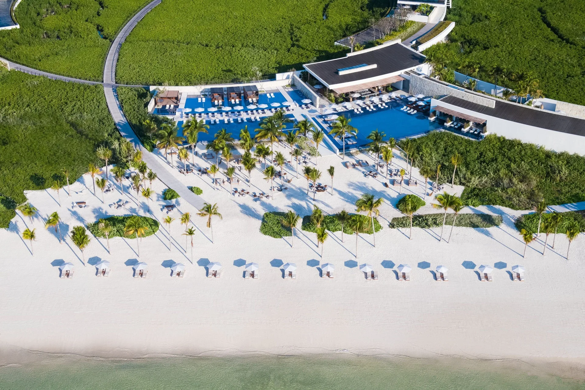Aerial view of the beachfront pool and white sand at The St. Regis Kanai Resort, Riviera Maya.