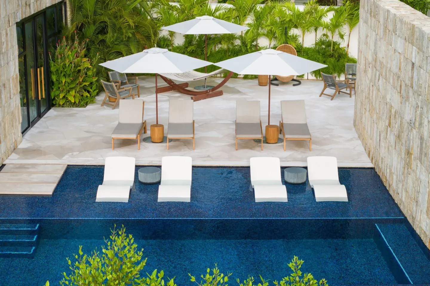 Poolside courtyard with loungers and umbrellas at The St. Regis Kanai Resort, Riviera Maya.