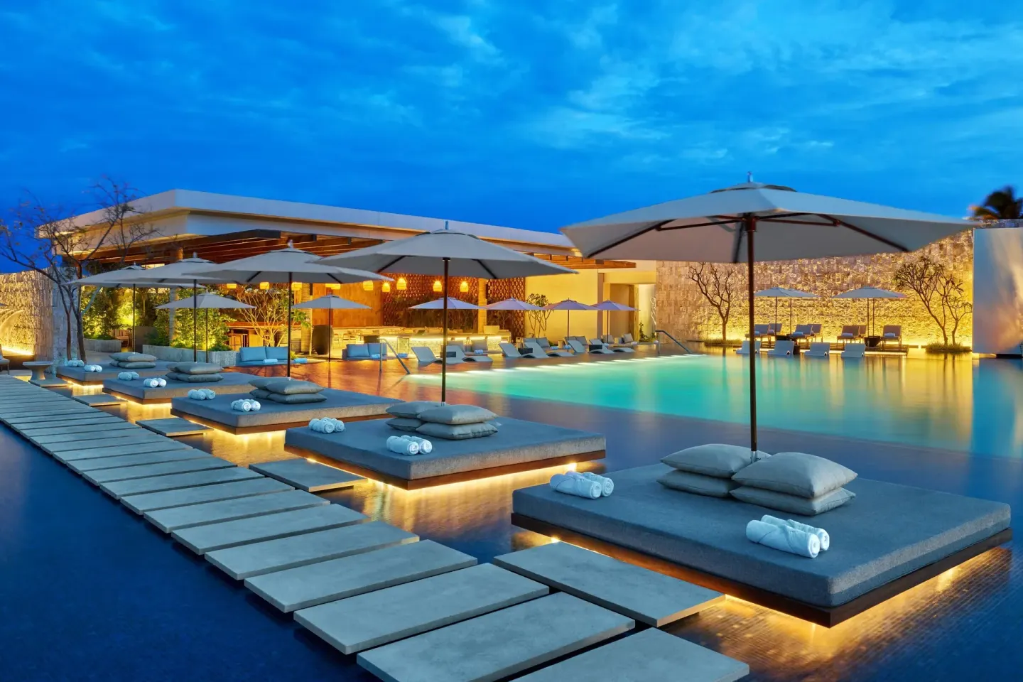 Illuminated pool loungers and umbrellas at The St. Regis Kanai Resort, Riviera Maya.