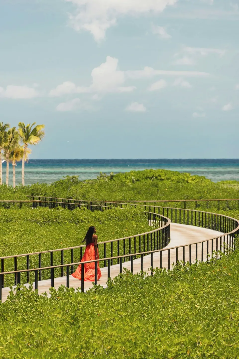 Curving boardwalk through mangroves toward the sea at The St. Regis Kanai Resort, Riviera Maya.