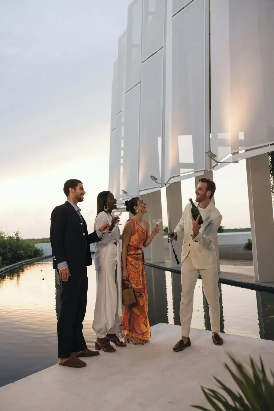 Guests toast with sparkling wine by reflective water at The St. Regis Kanai Resort, Riviera Maya.