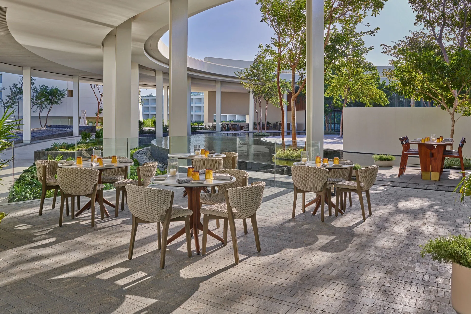 Outdoor restaurant terrace with set tables and reflecting water at The St. Regis Kanai Resort, Riviera Maya.