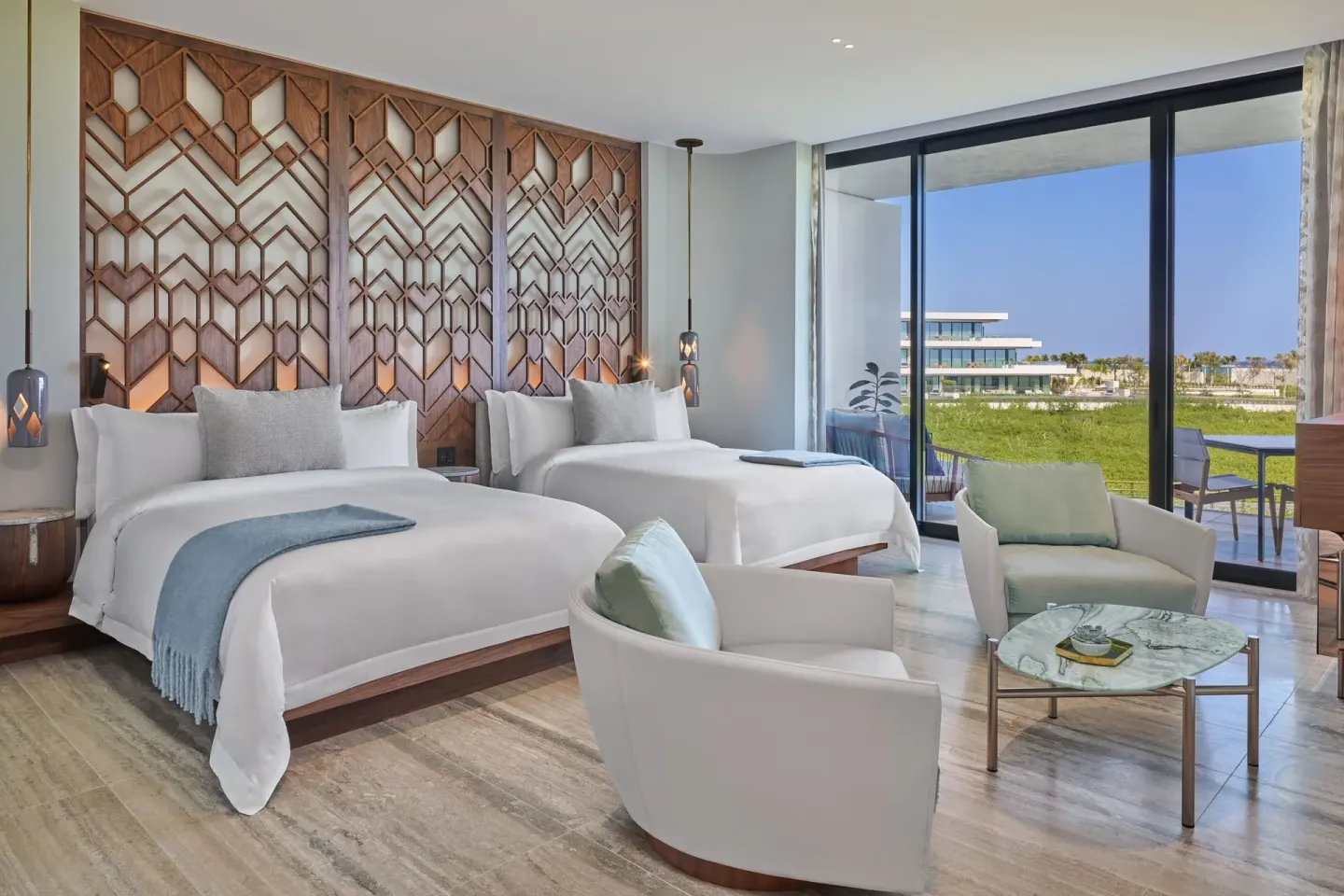 Deluxe Room with two beds, lounge chairs and terrace doors at The St. Regis Kanai Resort, Riviera Maya.