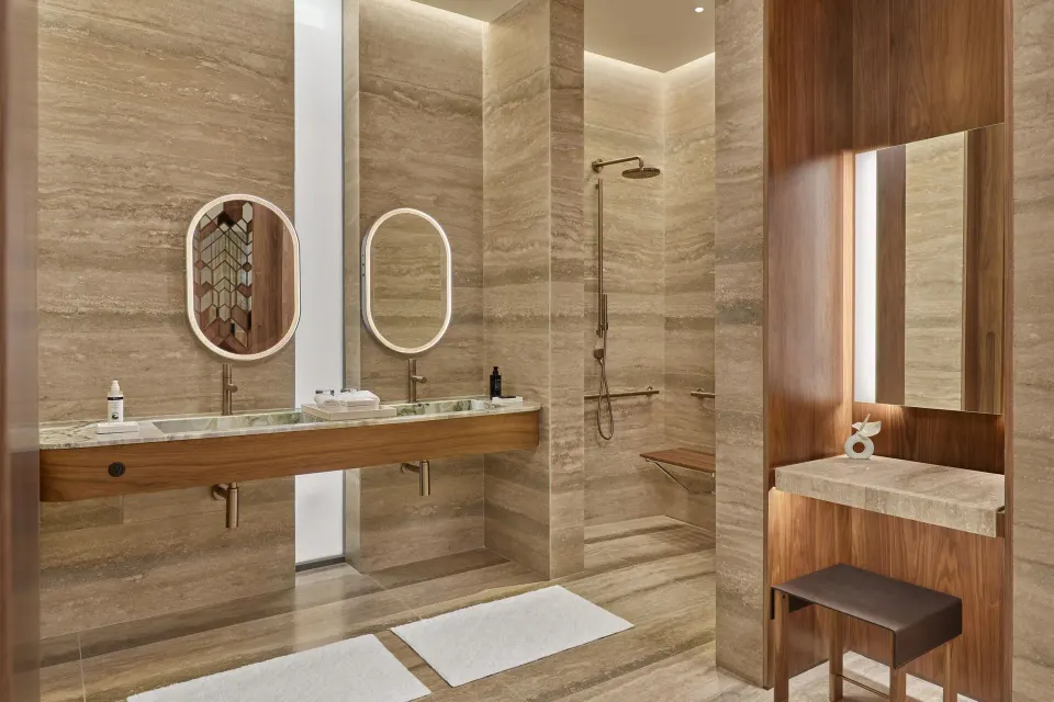 Stone bathroom with double vanity and walk-in shower at The St. Regis Kanai Resort, Riviera Maya.
