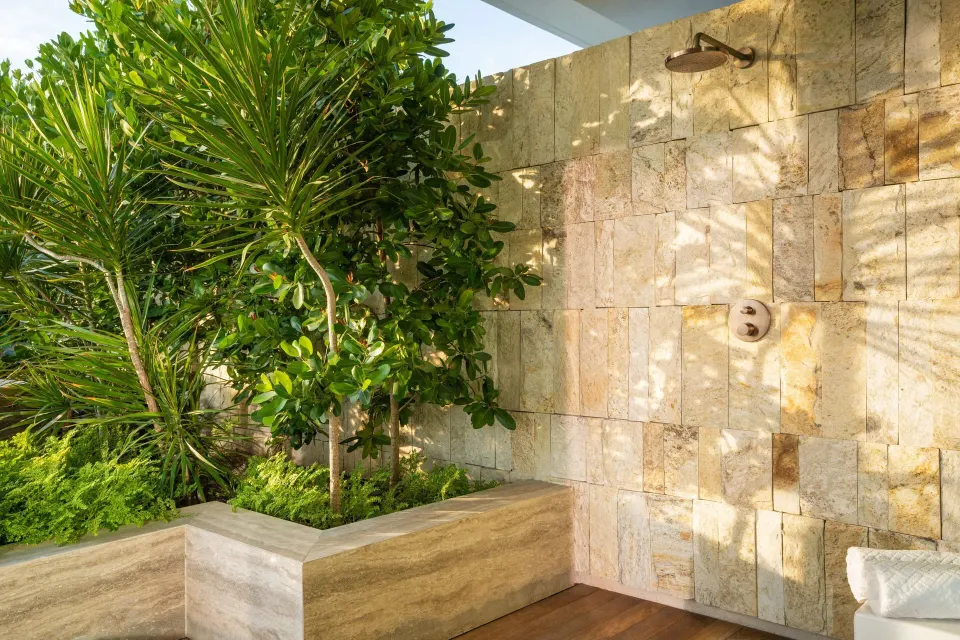 Outdoor shower with stone wall and tropical plants at The St. Regis Kanai Resort, Riviera Maya.