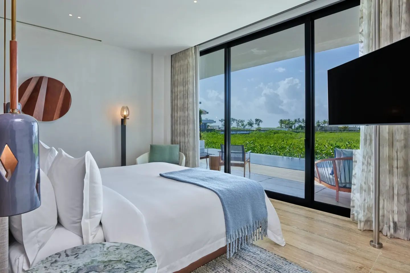Ocean View Suite king bed at The St. Regis Kanai Resort beside glass doors to the terrace.