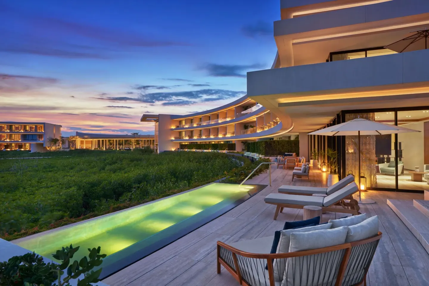 Ocean View Suite terrace at dusk with loungers and lit pool at The St. Regis Kanai Resort, Riviera Maya.