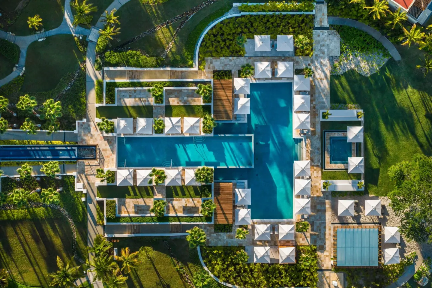 Aerial view of geometric pools, umbrellas and garden paths at The St. Regis Punta Mita Resort.