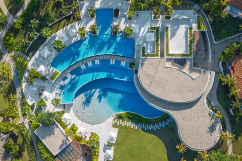Aerial view of curved pools, sun loungers and tropical landscaping at The St. Regis Punta Mita Resort.