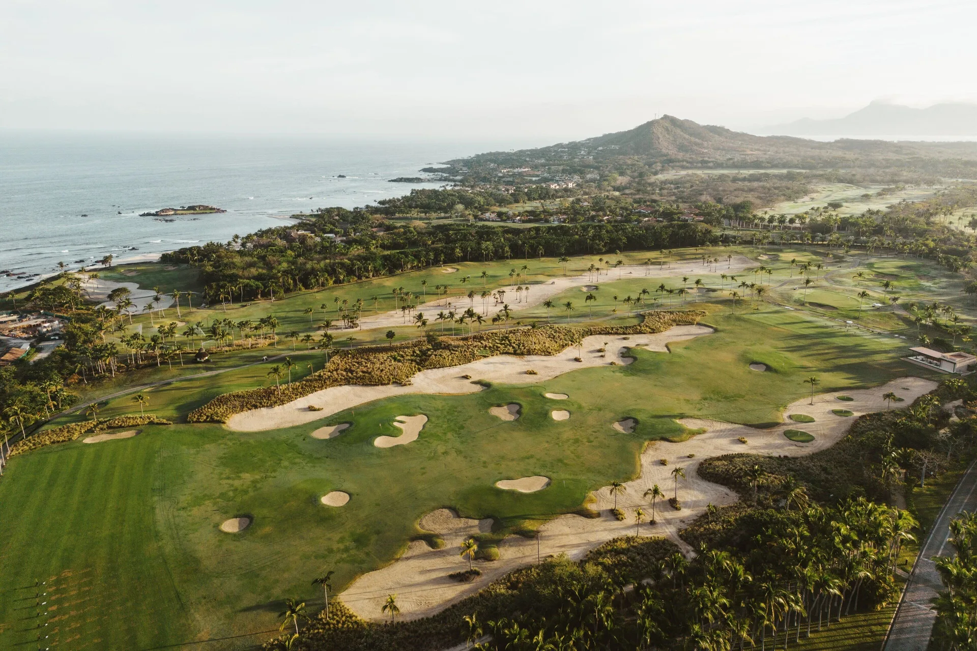 A coastal golf course stretches toward the ocean by The St. Regis Punta Mita Resort.
