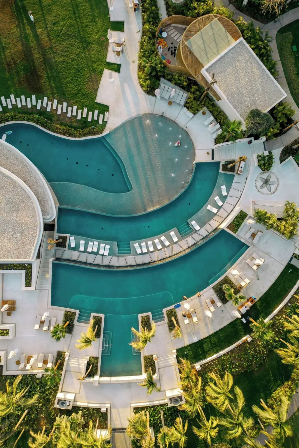 Overhead view of a curved pool deck with loungers at The St. Regis Punta Mita Resort.