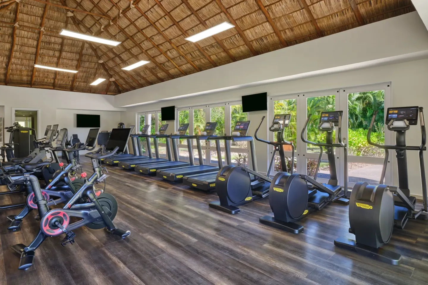 Fitness center with cardio machines beneath a thatched ceiling at The St. Regis Punta Mita Resort.