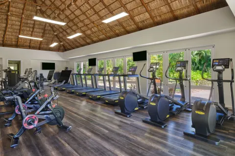 Fitness center with cardio machines beneath a thatched ceiling at The St. Regis Punta Mita Resort.
