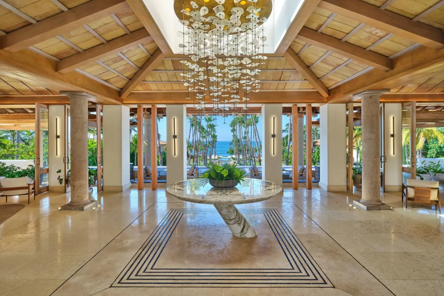 Open lobby with a hanging chandelier and ocean view at The St. Regis Punta Mita Resort.