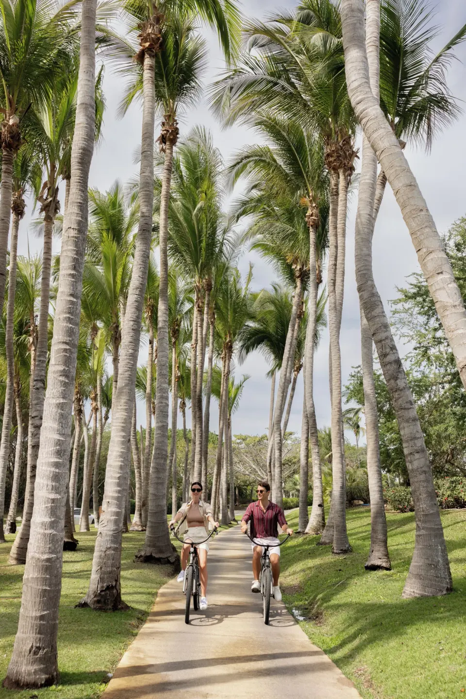 Guests bicycle beneath tall palms at The St. Regis Punta Mita Resort.