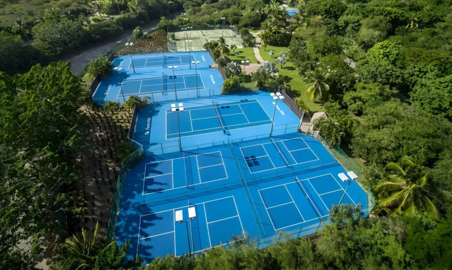 Blue tennis courts sit among tropical trees at The St. Regis Punta Mita Resort.