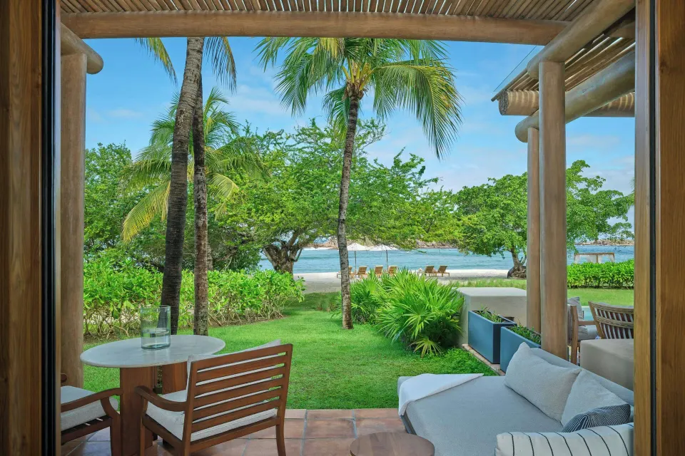 Beachfront room terrace with lawn, palms, and beach view at The St. Regis Punta Mita Resort.