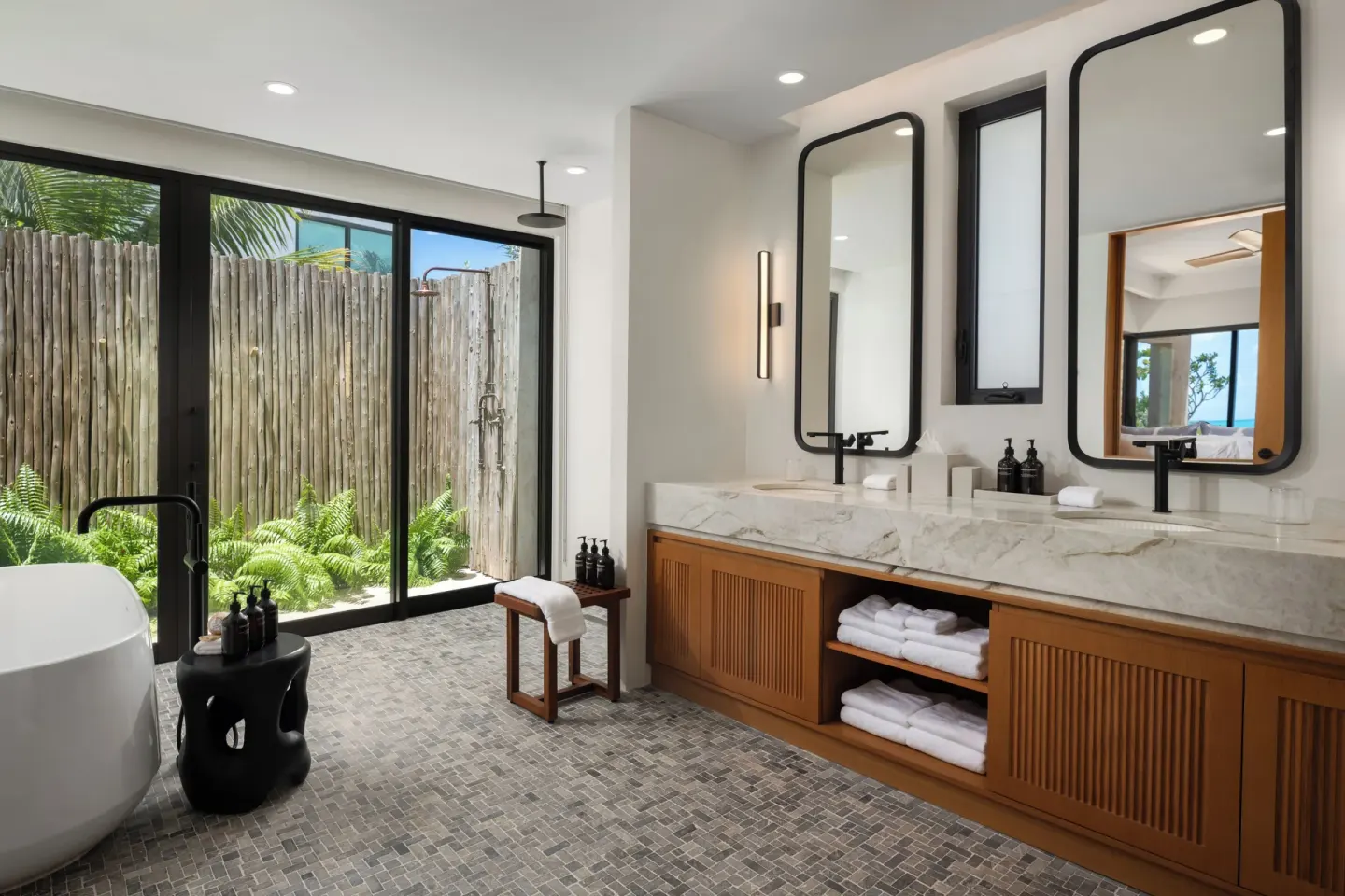 Bathroom with freestanding tub, double vanity, and outdoor shower at The Strand Turks and Caicos.