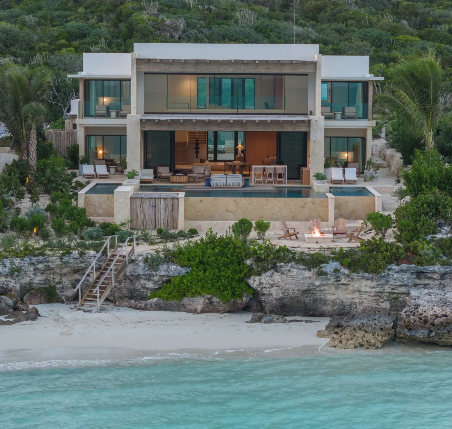 Beachfront villa with pool, terraces, and rocky shoreline at The Strand Turks and Caicos.