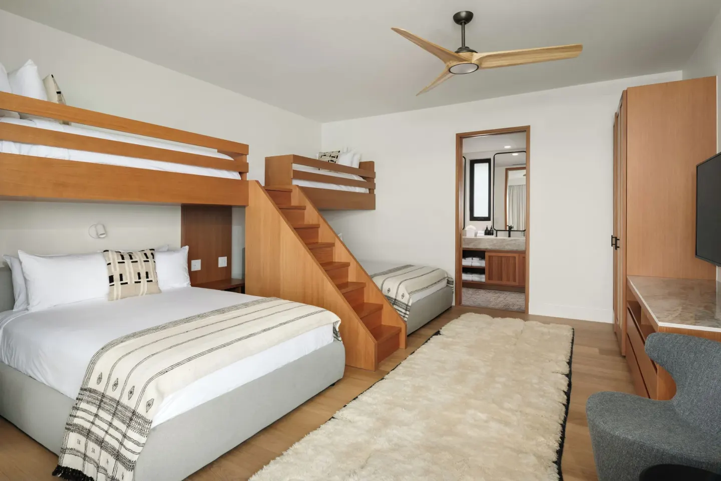 Bunk guest room with queen bed and open bathroom door at The Strand Turks and Caicos.