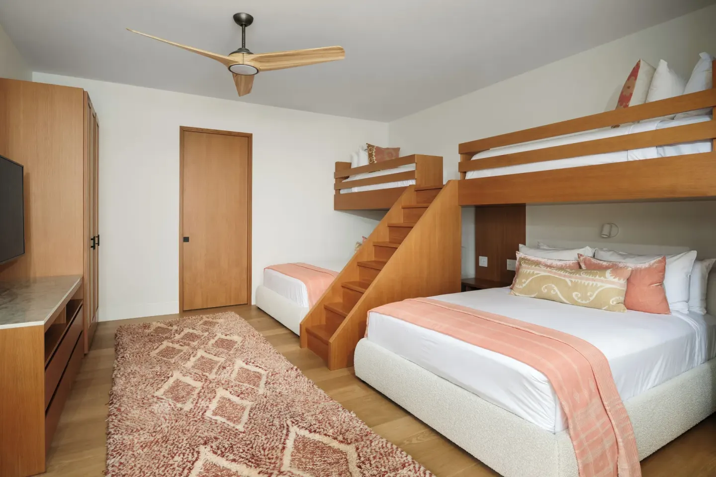 Bunk guest room with queen bed and coral accents at The Strand Turks and Caicos.