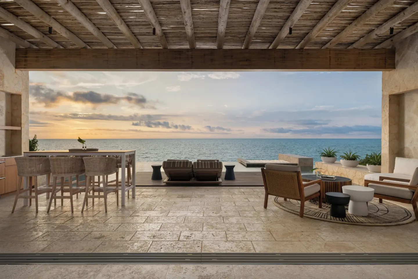 Covered oceanfront patio with dining and lounge seating at The Strand Turks and Caicos.