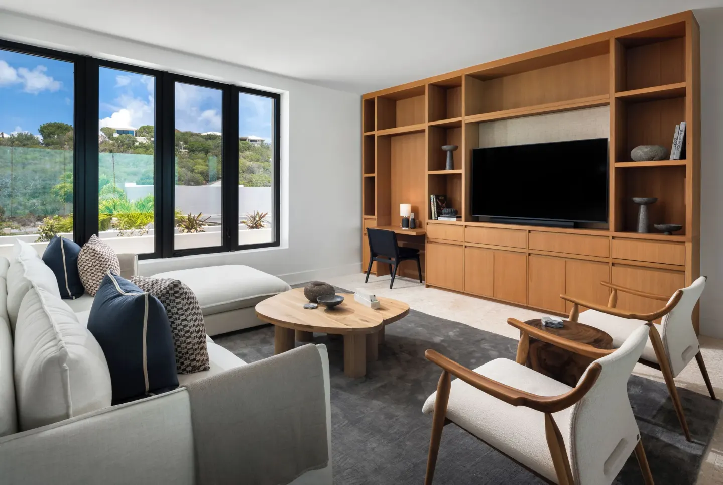 Lounge with wood media wall and garden-facing windows at The Strand Turks and Caicos.