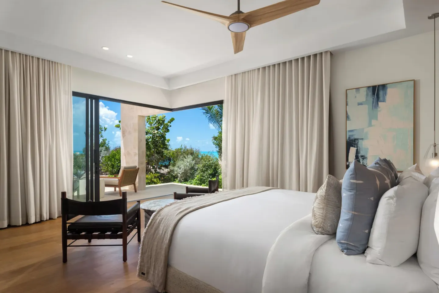 Guest room with king bed and open terrace facing the water at The Strand Turks and Caicos.