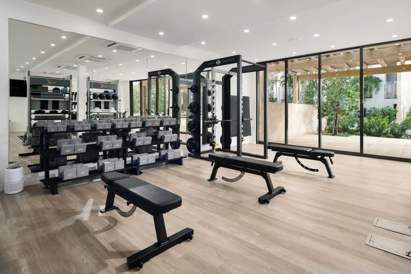 Gym with dumbbells, benches, mirrors, and garden views at The Strand Turks and Caicos.