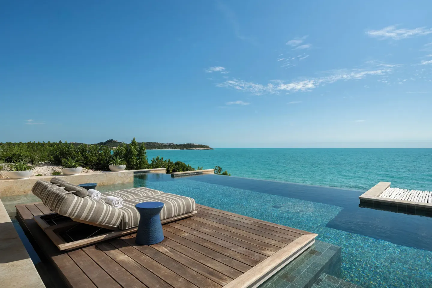 Infinity pool with cushioned loungers overlooking the ocean at The Strand Turks and Caicos.