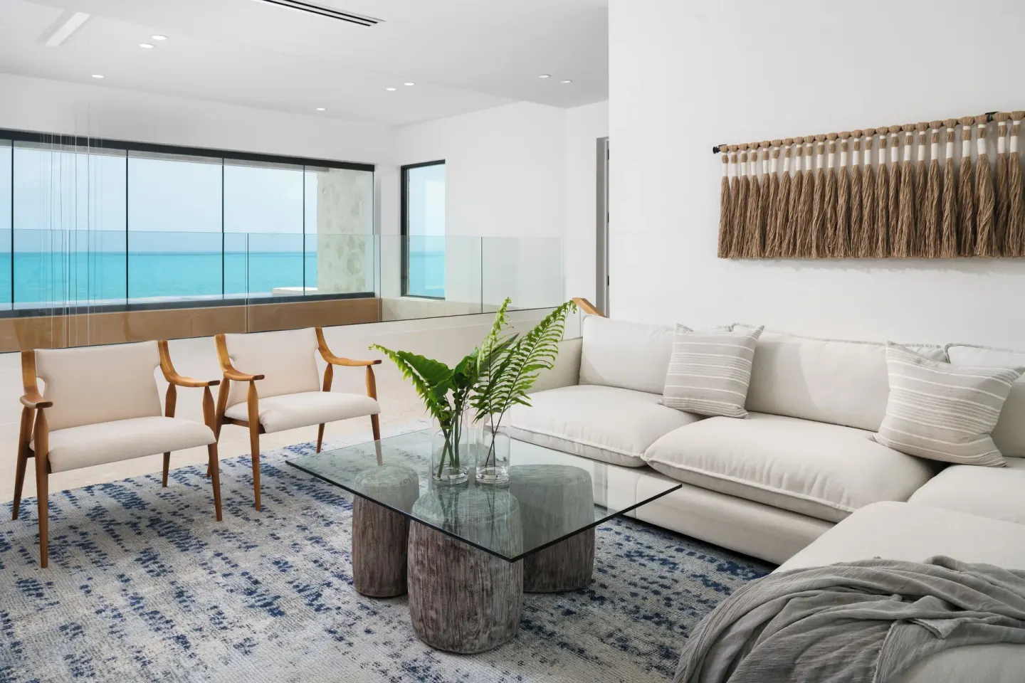 Ocean-view sitting area with white sofa and glass coffee table at The Strand Turks and Caicos.