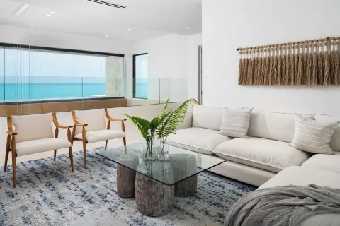 Ocean-view sitting area with white sofa and glass coffee table at The Strand Turks and Caicos.