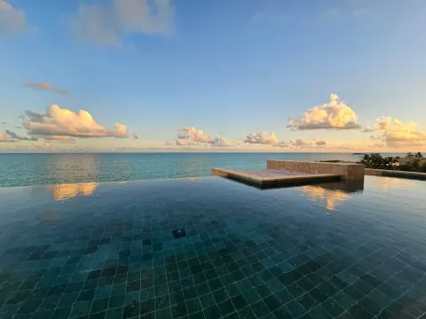 Infinity pool reflecting sunset clouds over the ocean at The Strand Turks and Caicos.