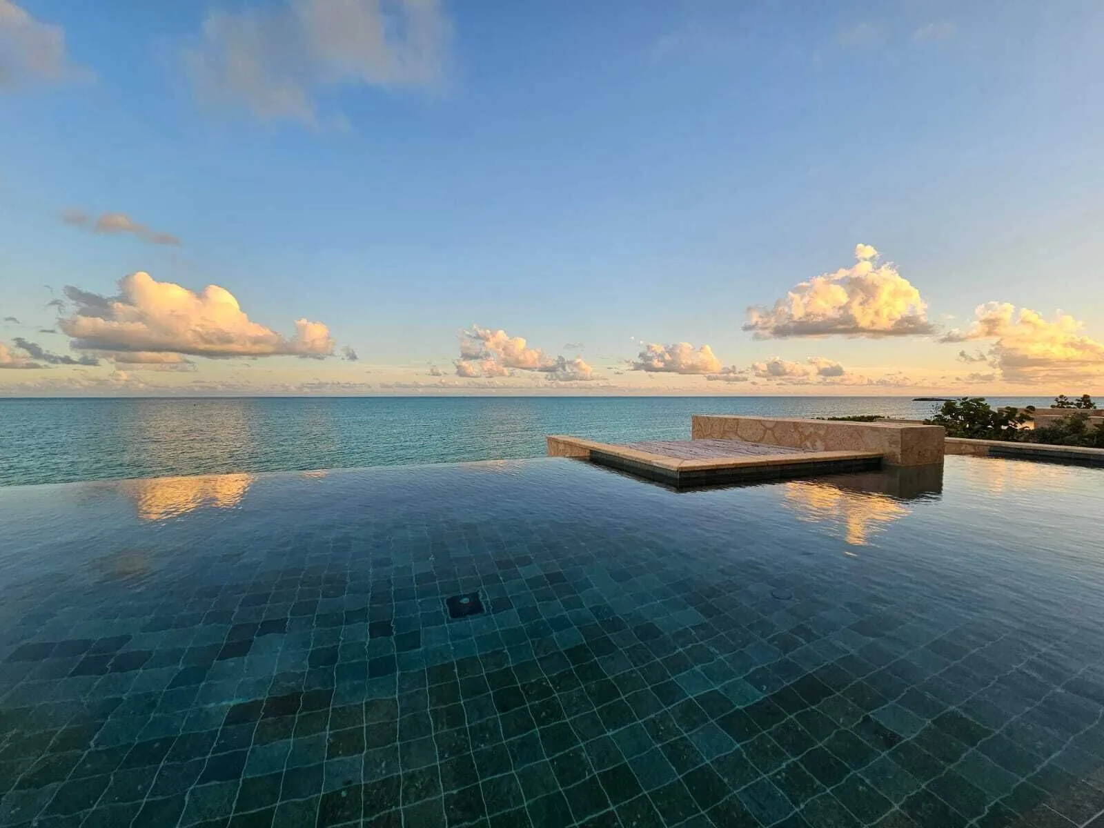 Infinity pool reflecting sunset clouds over the ocean at The Strand Turks and Caicos.