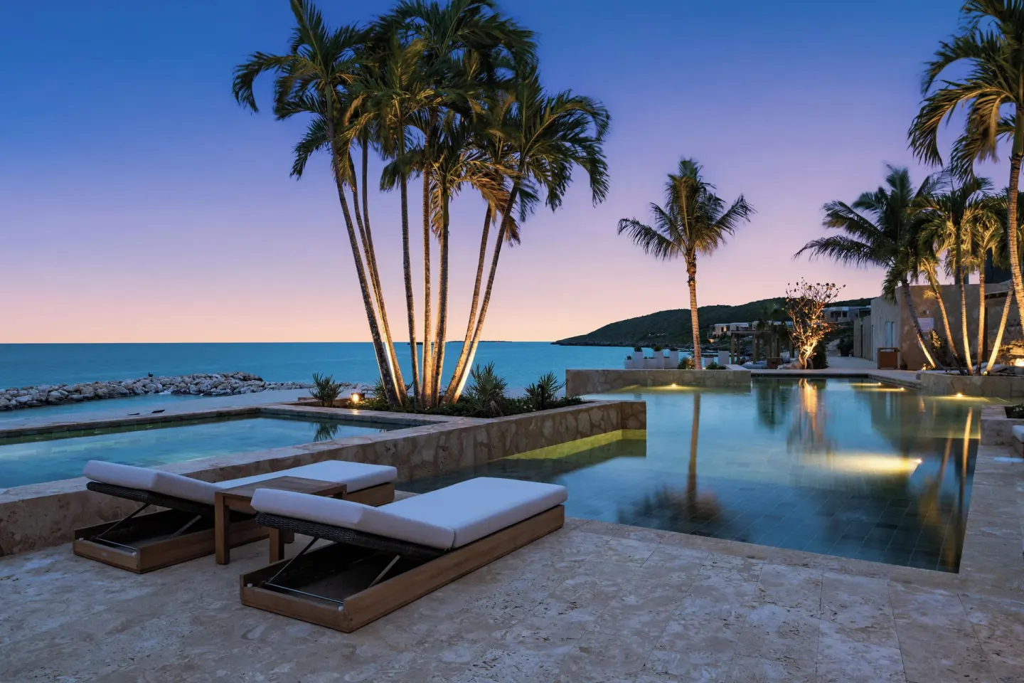 Twilight pool terrace with palms and ocean view at The Strand Turks and Caicos.