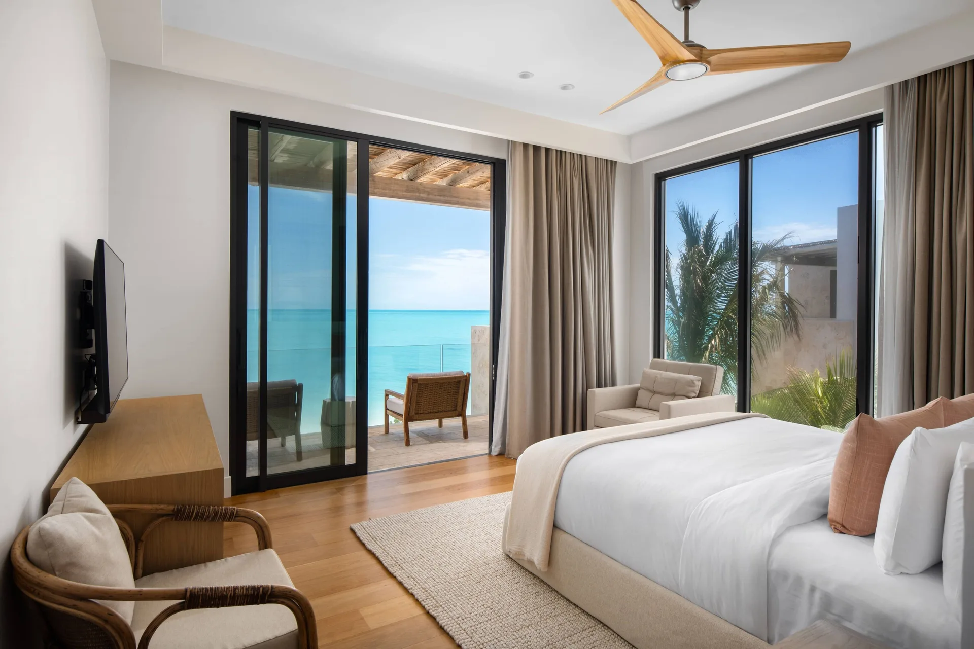 King bedroom with ocean balcony, TV, and seating at The Strand Turks and Caicos.