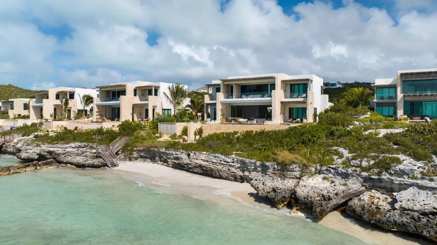 Beachfront grand residence buildings at The Strand Turks and Caicos above turquoise water.