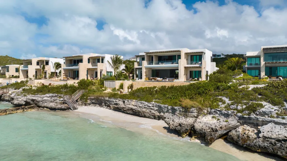 Beachfront grand residence buildings at The Strand Turks and Caicos above turquoise water.