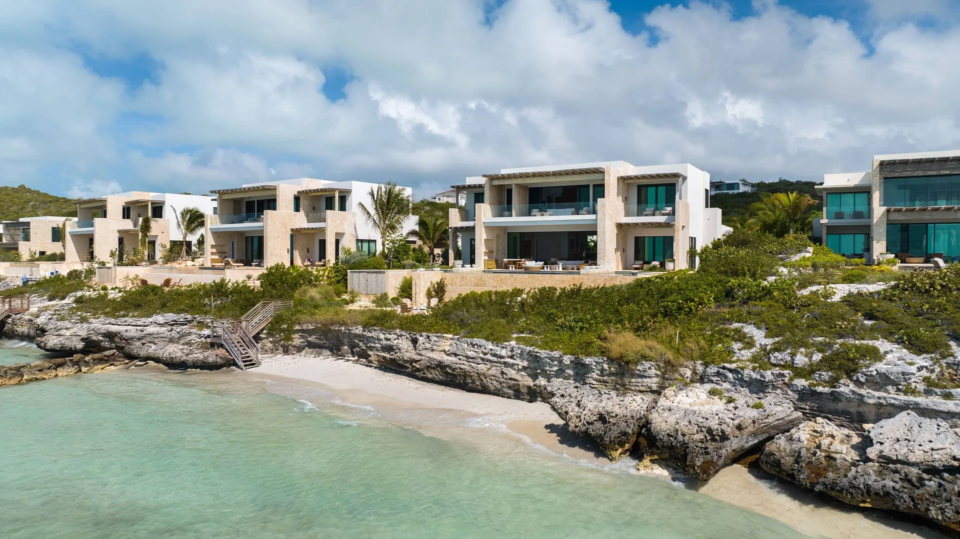 Beachfront grand residence buildings at The Strand Turks and Caicos above turquoise water.