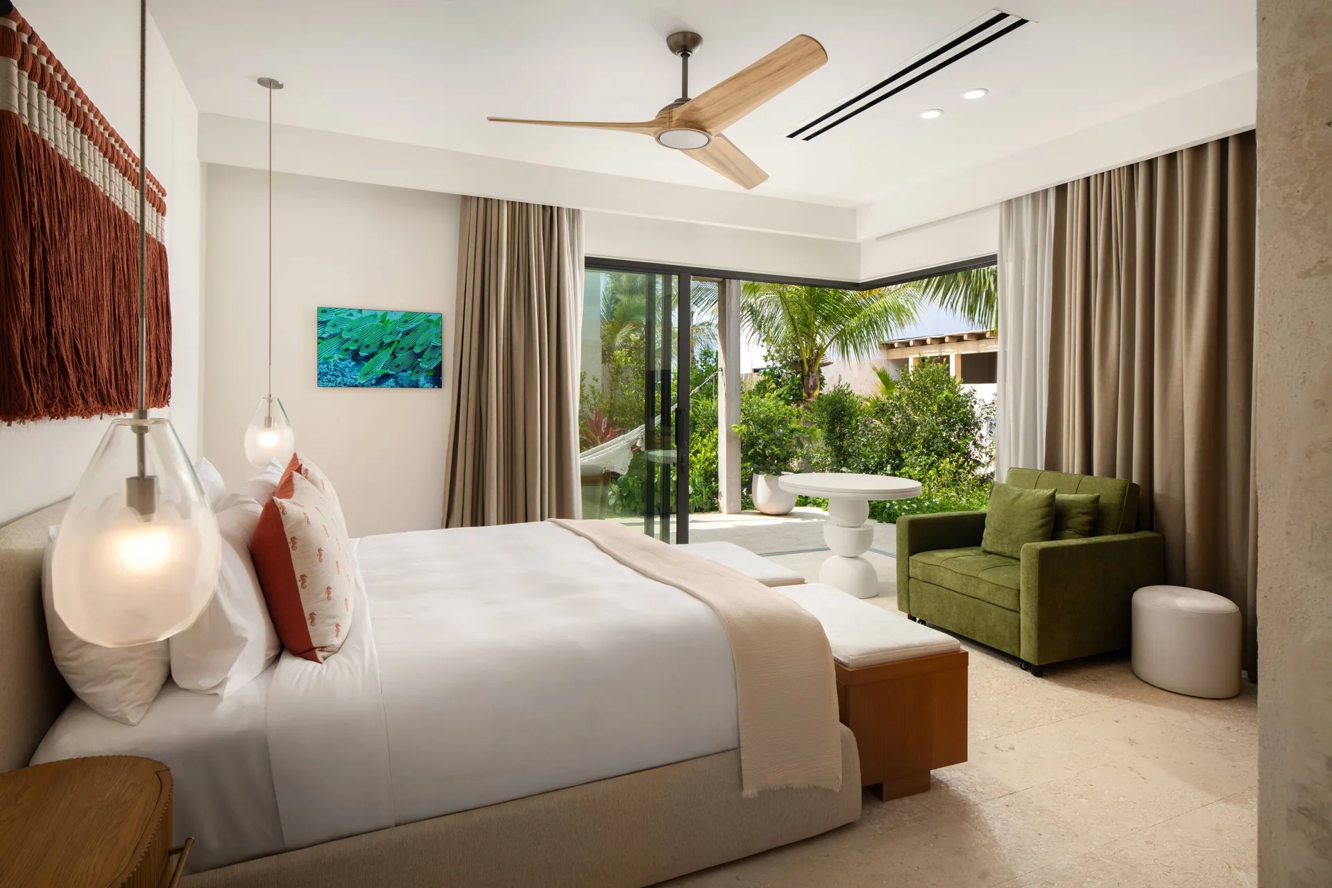 Bedroom with king bed, green sofa, and garden patio at The Strand Turks and Caicos.