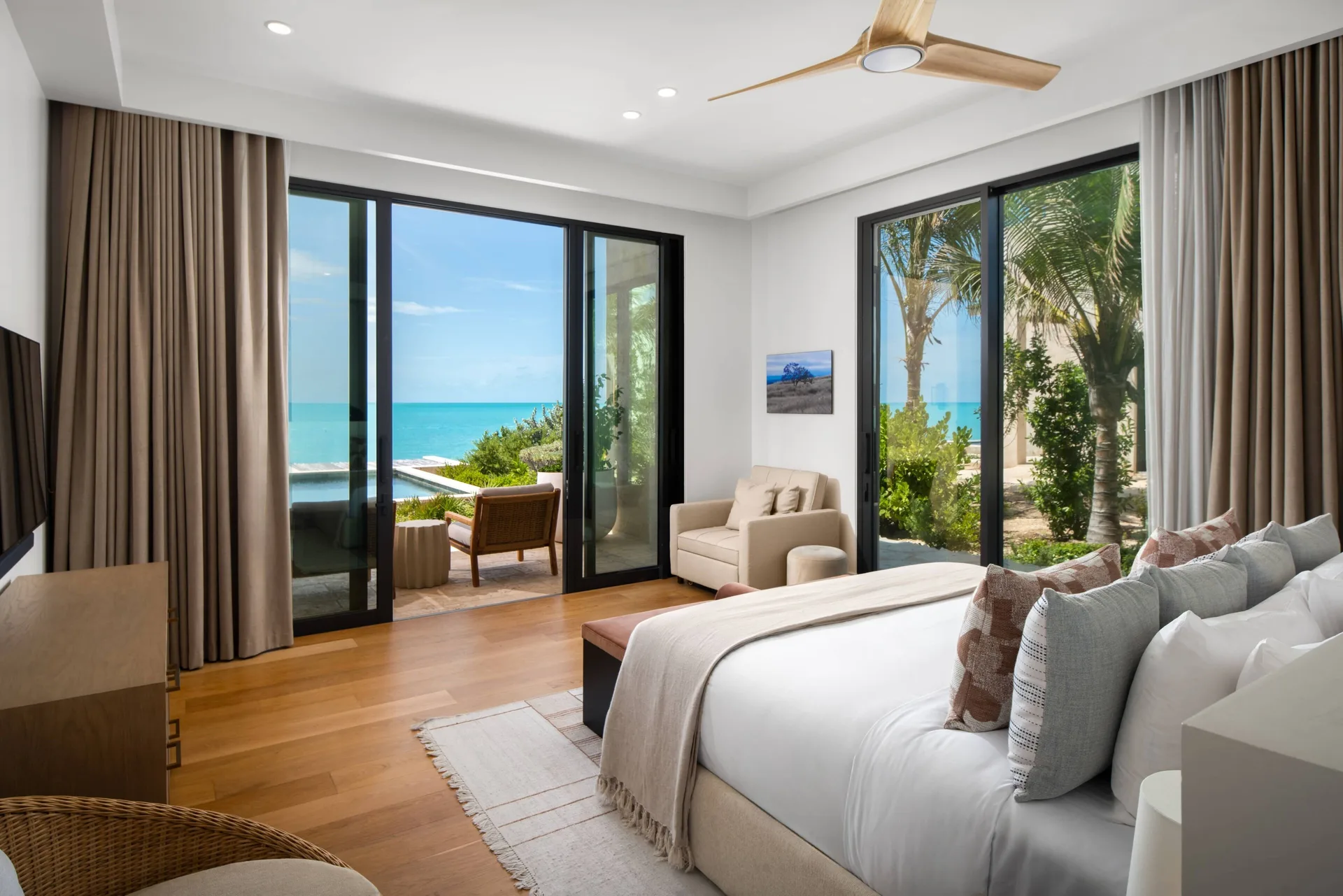 Ocean-view king bedroom with palm trees and balcony at The Strand Turks and Caicos.