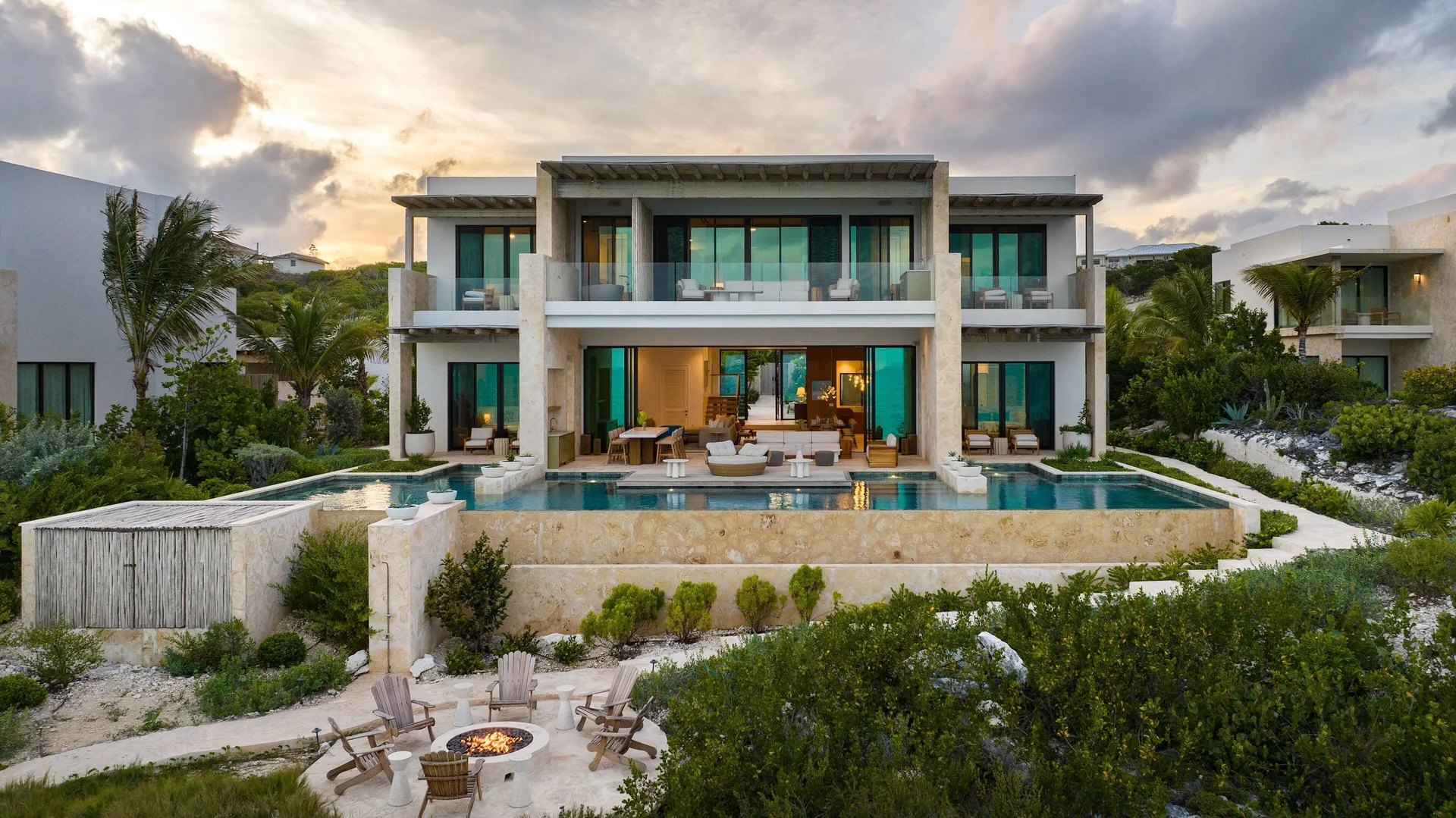 Grand Residence beachfront exterior with pool and fire pit at The Strand Turks and Caicos.
