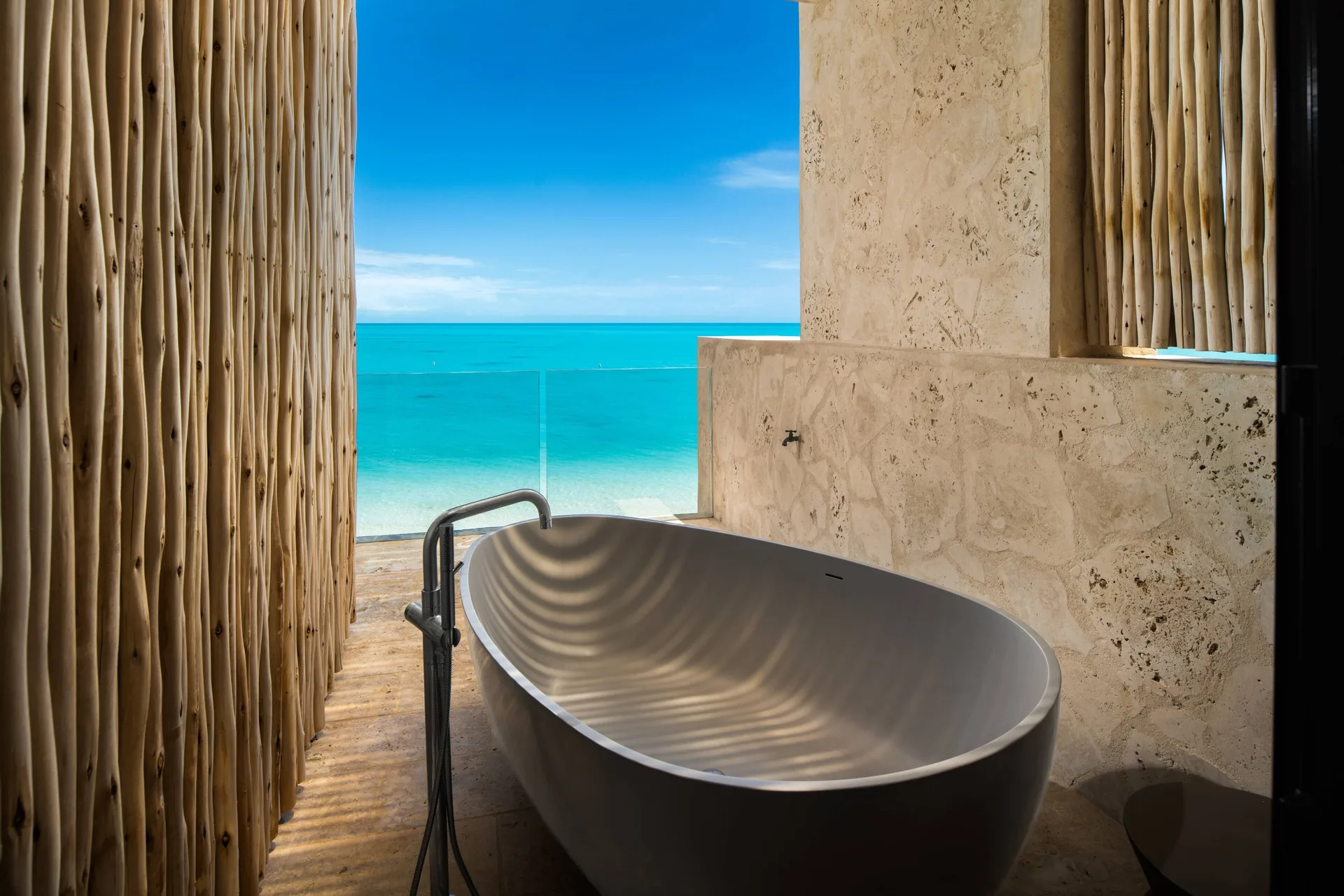 Outdoor soaking tub with turquoise ocean view at The Strand Turks and Caicos.